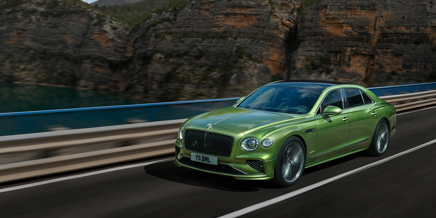 Bentley Bucuresti Bentley New Flying Spur Speed v8 hybrid sedan driving dynamically on a mountain road in Tourmaline Green paint