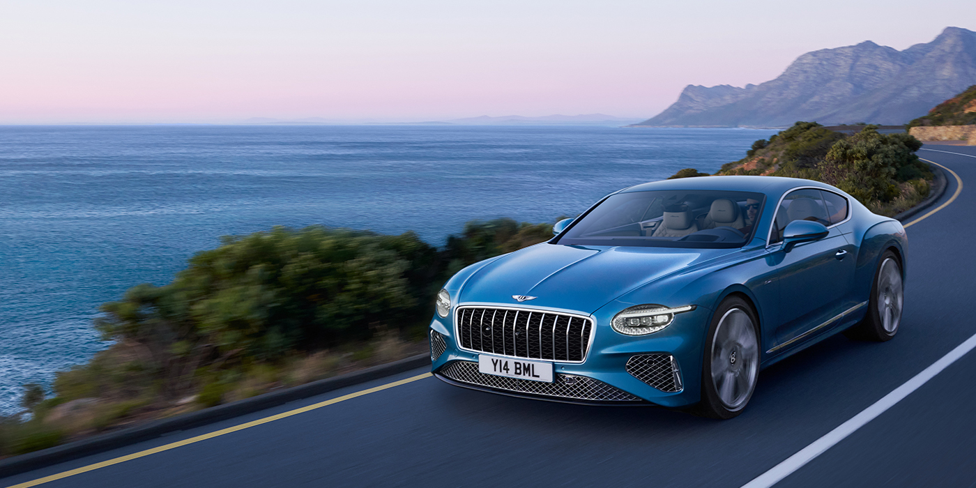 Bentley Bucuresti New Bentley Continental GT Azure coupe in Light Windsor blue paint with 22 inch Azure wheels and chrome grill, driving dynamically by the sea