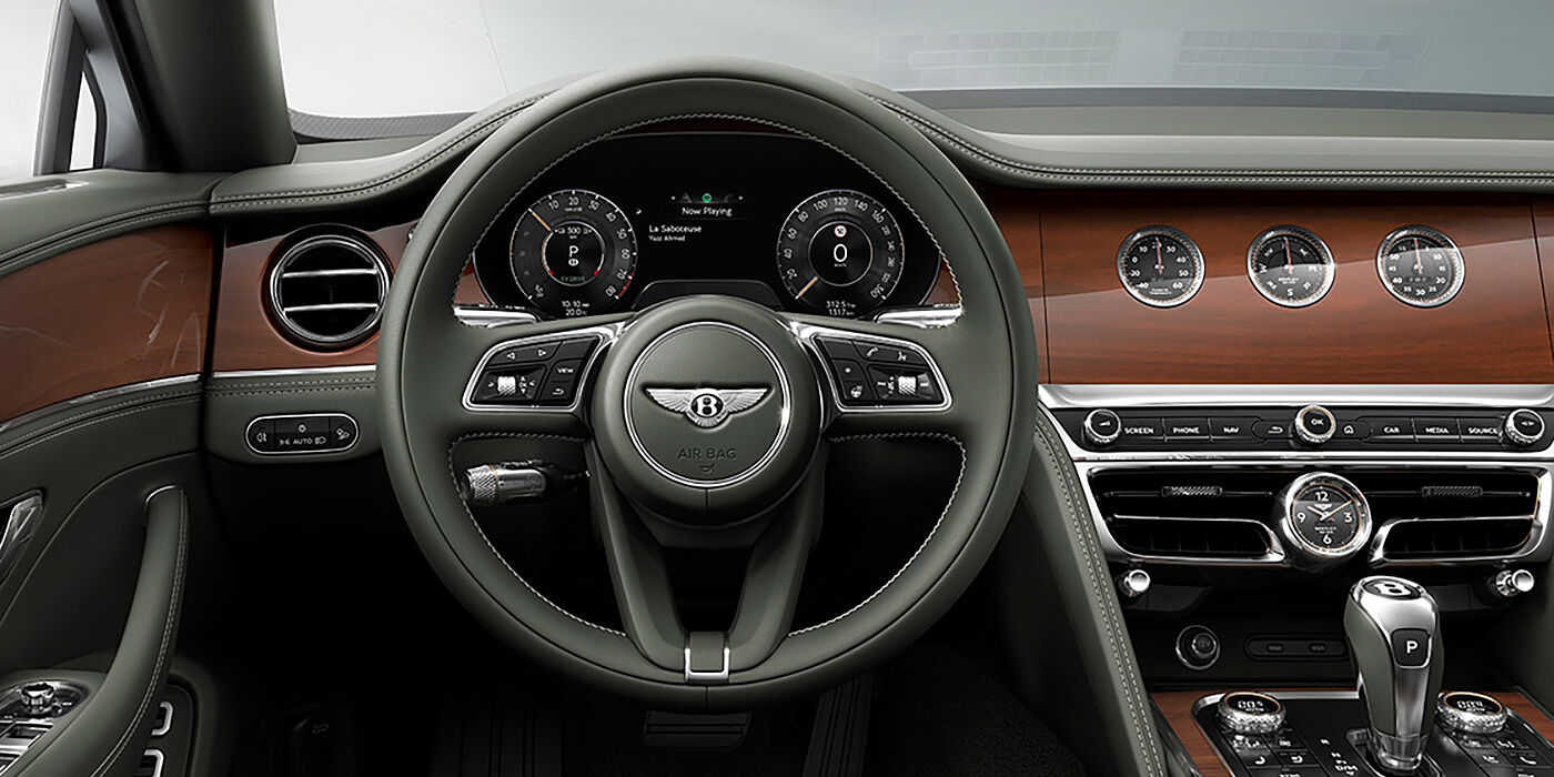 Bentley Bucuresti New Bentley Flying Spur sedan front cabin in Cumbrian Green hide and Crown Cut walnut veneer showing steering wheel and Rotating Display with three clocks on face