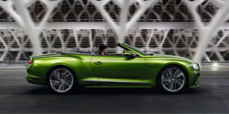 Bentley Bucuresti Bentley Continental GTC Speed convertible side profile in Tourmaline Green paint driving dynamically on a bridge at night