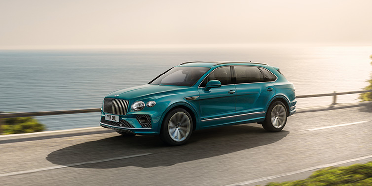 Bentley Bucuresti Bentley Bentayga Extended Wheelbase Azure SUV in Topaz blue paint driving dynamically by the ocean