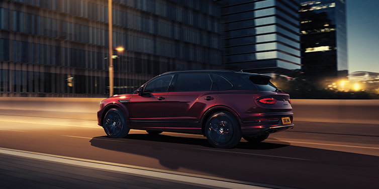 Bentley Bucuresti Bentley Bentayga Extended Wheelbase Mulliner SUV in Cricket Ball red paint driving dynamically in city at night