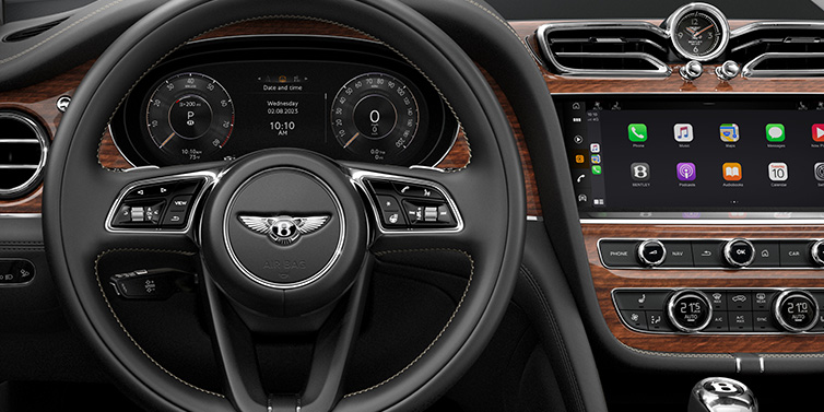 Bentley Bucuresti Bentley Bentayga SUV front interior detail of steering wheel and driver screens surrounded by Beluga black hide and Crown Cut Walnut veneer